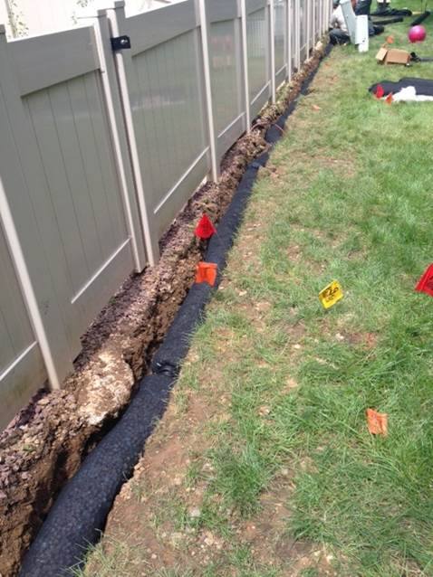 french drain installation along a white fence